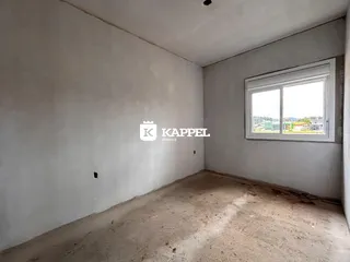 Foto de um cômodo interno com paredes brancas e piso cru.