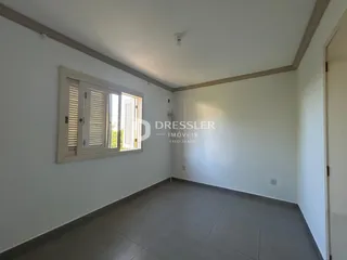 Sala de estar com janela e paredes brancas em imóvel no Brasil