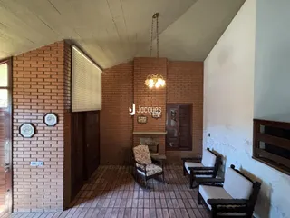 Interior de uma sala com paredes de tijolo aparente e piso cerâmico.