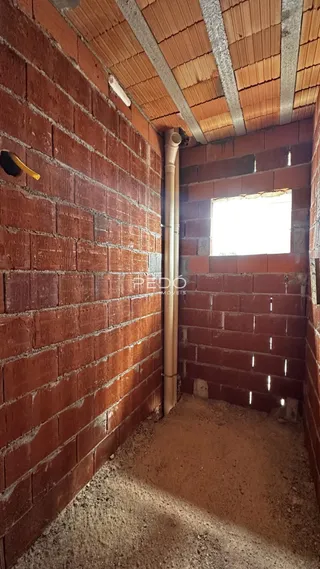 Interior com paredes de tijolo aparente e piso de terra em uma construção.