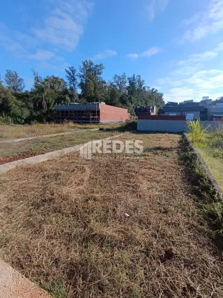 Vista externa de um terreno com grama seca e terra no Brasil.