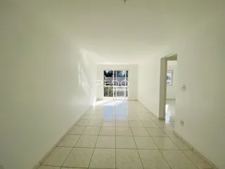 Corredor interno com piso de cerâmica clara e paredes brancas.