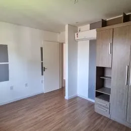Ambiente interno com piso de madeira e armário embutido na parede.