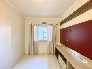 Interior de um ambiente com parede de destaque e janela coberta por cortinas brancas.