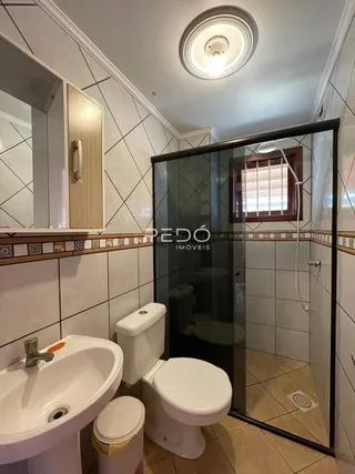 Foto de um banheiro com azulejos brancos e box de vidro.