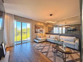Sala de estar com piso de madeira e grandes janelas que dão vista para a natureza.