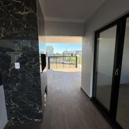 Hall de entrada com piso de madeira e porta de vidro.