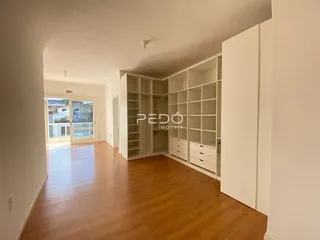 Hall de entrada com piso de madeira e estantes brancas embutidas.