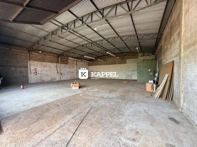 Espaço amplo e industrial com piso de concreto e estrutura metálica exposta.