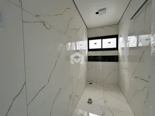 Corredor interno com revestimento em mármore branco nas paredes e piso.
