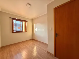 Uma sala de estar com piso de madeira clara e janela.