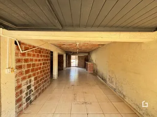 Corredor interno com piso de cerâmica e parede de tijolo aparente.
