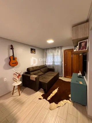 A sala de estar possui um sofá marrom e piso de madeira.