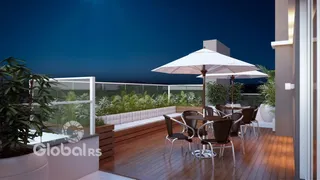 Vista noturna de uma varanda com mobiliário de exterior e mesas sob guarda-sóis.