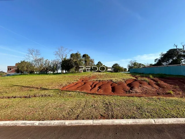 Vista de um terreno com terra avermelhada e grama no primeiro plano.