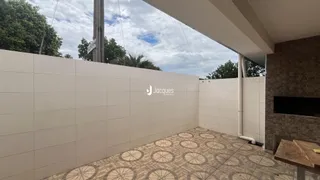 Vista de uma área externa com piso de cerâmica e parede branca.