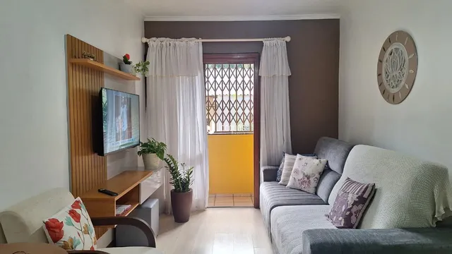 Sala de estar com cortinas brancas e sofá em ambiente claro.