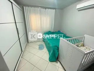 Quarto interno com cama e janela coberta por persianas brancas.