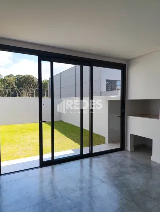 Vista interna de uma sala com portas de vidro que se abre para um jardim.