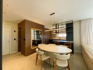 Sala de jantar com mesa branca e painéis de madeira na área interna da residência.