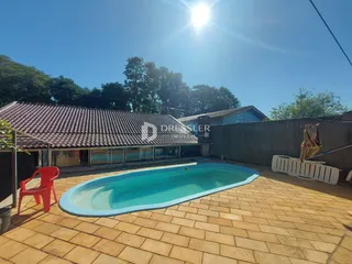 Piscina externa com área de piso de tijolos no exterior de uma residência.