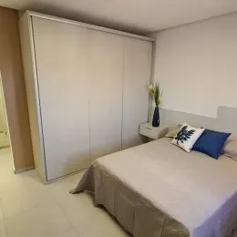 Quarto com cama grande e armário embutido em ambiente claro.