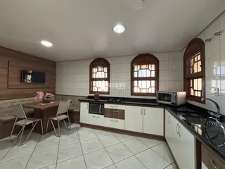 Ambiente interno de uma sala de estar com cozinha integrada e área de jantar.