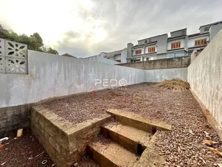 Vista externa de um terreno com muro e degraus de concreto.