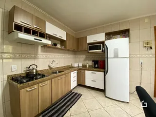 Vista interna de uma cozinha com armários e eletrodomésticos.