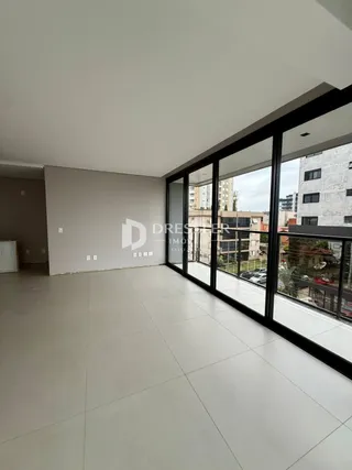 Ambiente interno amplo com piso claro e grandes janelas de vidro.