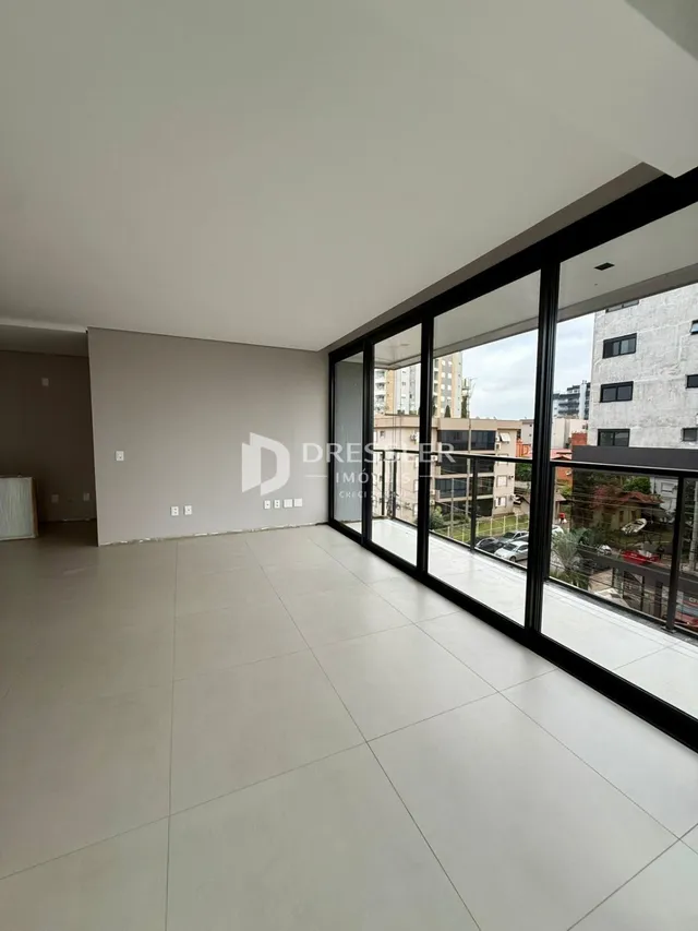 Ambiente interno amplo com piso claro e grandes janelas de vidro.