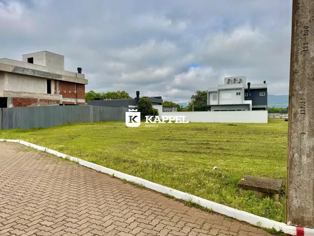 Vista externa de uma propriedade residencial com gramado e construções ao fundo.