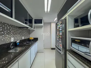 Cozinha moderna com armários brancos e bancadas escuras.