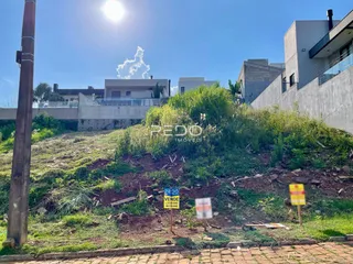 Vista externa de uma propriedade com declive e vegetação ao fundo.