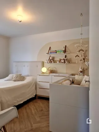 Quarto com cama e decoração de madeira clara.