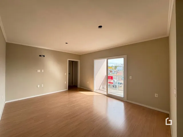 Sala de estar com piso de madeira e porta de vidro abrindo para o exterior.