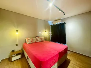 Quarto com cama de casal e piso de madeira clara.