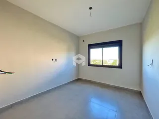 Vista interna de uma sala com paredes brancas e piso de concreto.