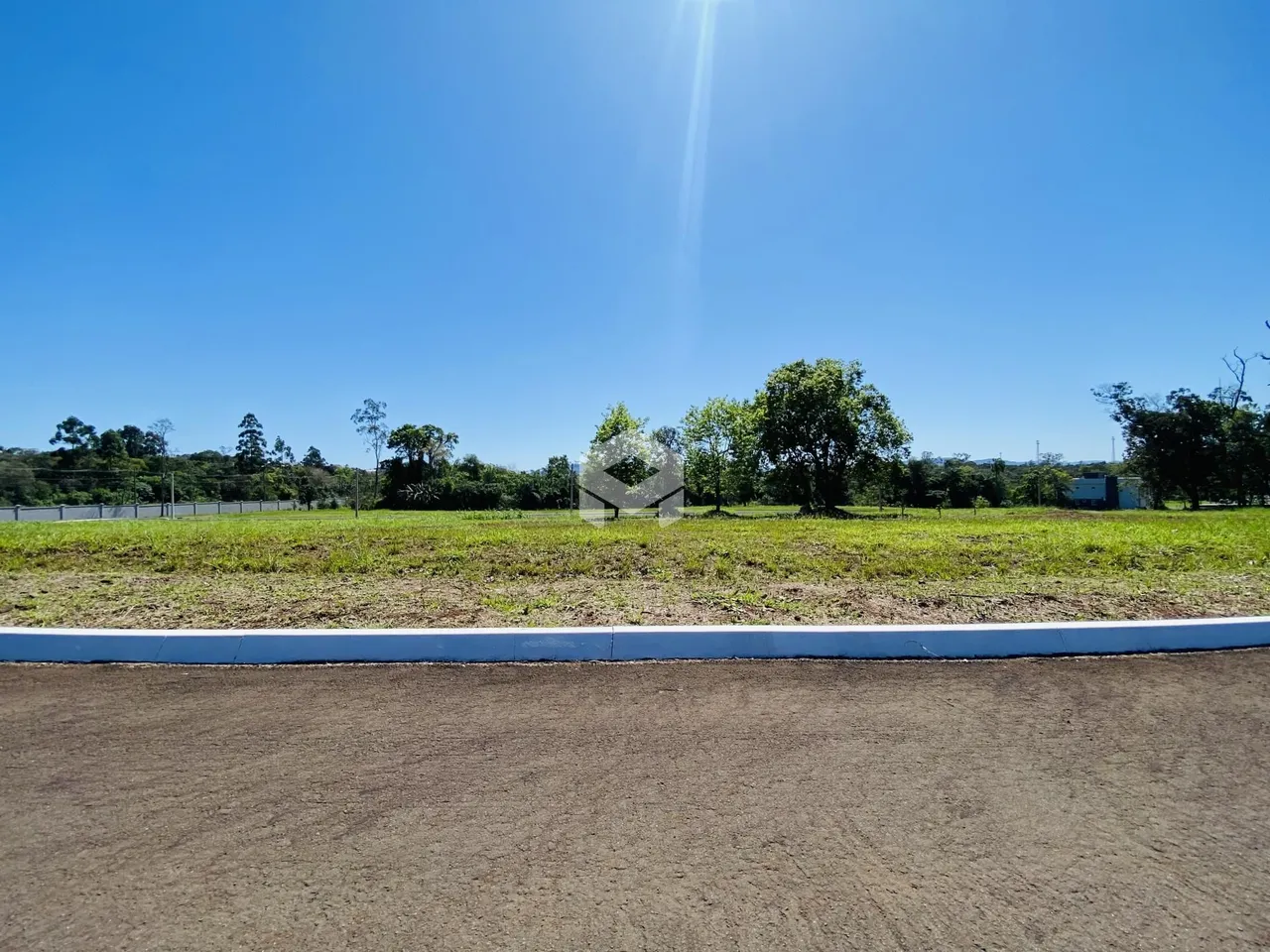 Paisagem de campo com vegetação e céu azul ao fundo.