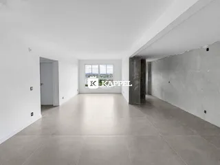 Sala ampla com piso claro e vista para a paisagem externa.