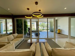 Sala de estar com sofá e grandes portas de vidro que dão vista para o exterior.