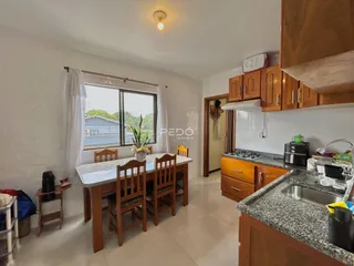 Foto de uma sala de jantar com mesa de madeira e cozinha em um imóvel no Brasil.