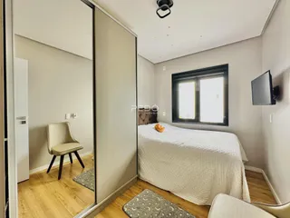 Quarto com cama e janela em ambiente claro.