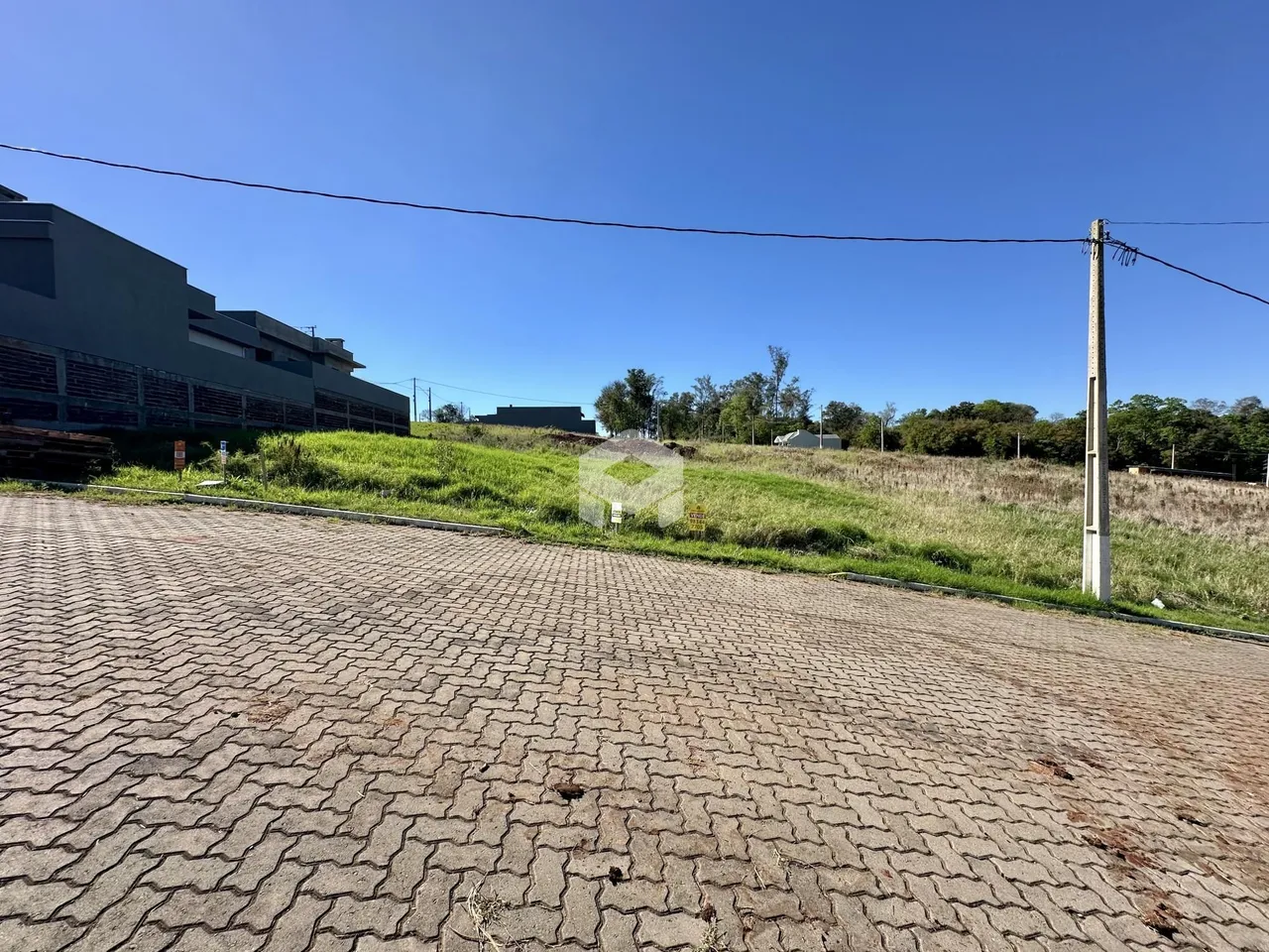 Vista externa de uma propriedade com terreno gramado e pavimentação.