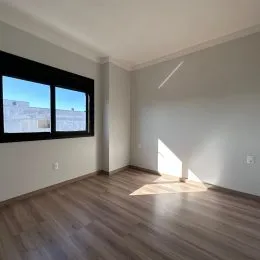 Foto de uma sala com piso de madeira e grande janela.