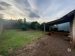 Vista externa de um terreno com gramado e vegetação ao pôr do sol.