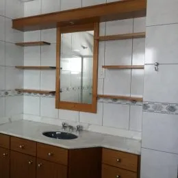 Parede interna com painéis de madeira e espelho em um ambiente residencial.