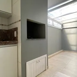 Sala de estar com parede cinza e televisão montada na parede.