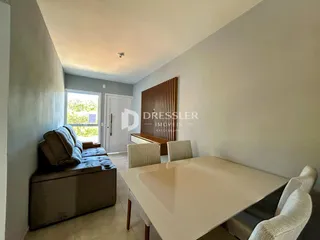 A sala de estar mostra um sofá e uma mesa de jantar em um ambiente claro.