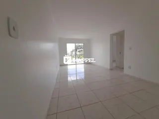 Vista interna de um corredor amplo com piso de cerâmica e uma grande janela.